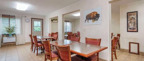A dining area with a large table and chairs, a clock on the wall, and a buffalo painting.