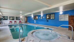 Una piscina interior con un jacuzzi, agua cristalina y una pared azul con ventanas y un letrero.