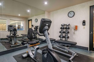 Un gimnasio con equipo de ejercicio, un reloj y un teléfono en la pared.