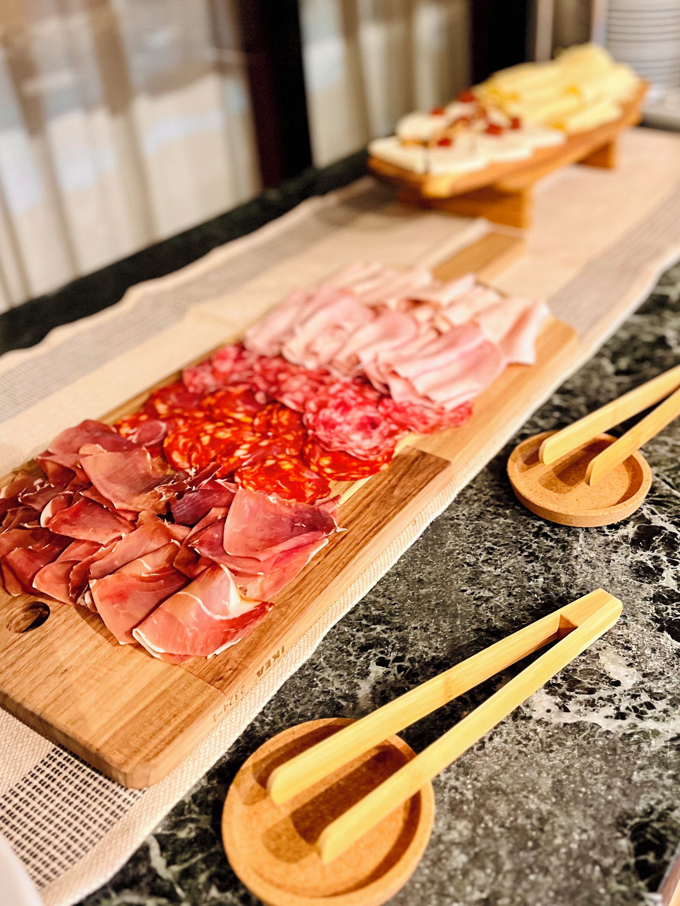 Una tabla de madera con diversos tipos de carne y queso sobre una encimera de mármol.