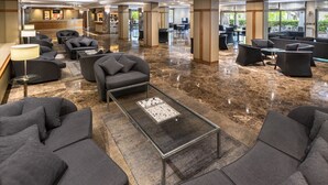 Un amplio vestíbulo con varias zonas de estar, un mostrador de recepción y una decoración de diseño moderno.