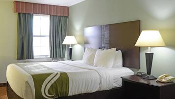 A hotel room with a large bed, two bedside lamps, a nightstand with a phone, and a window with curtains.