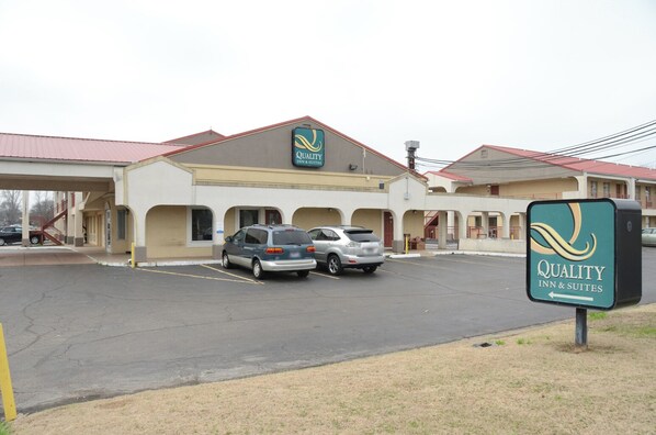 A Quality Inn & Suites with a parking lot, two cars parked, and a signboard.