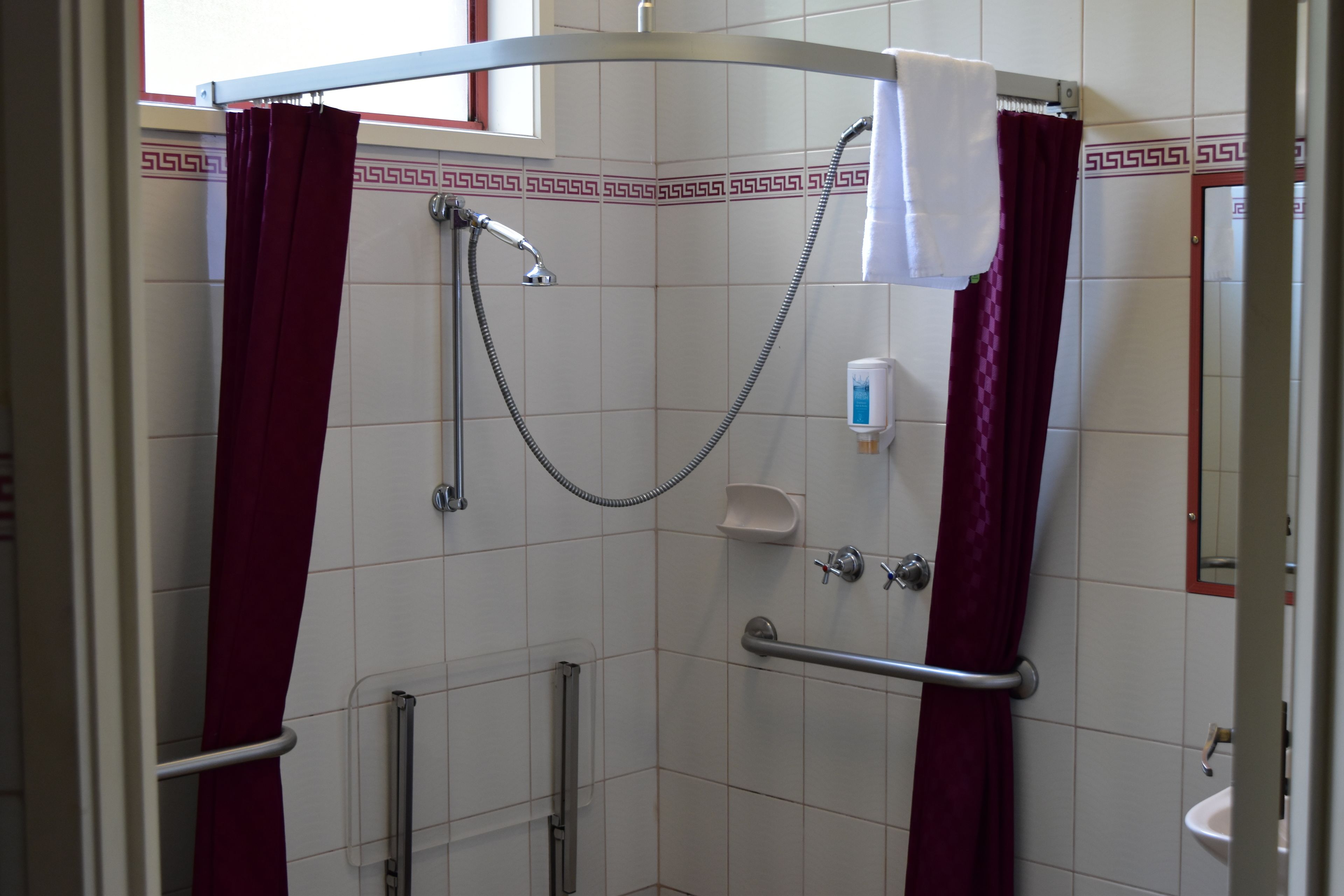 A shower with a handheld showerhead, a handheld showerhead, and a handheld showerhead.