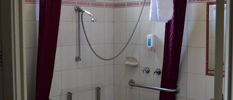 Una ducha con tres cabezales de ducha manuales.