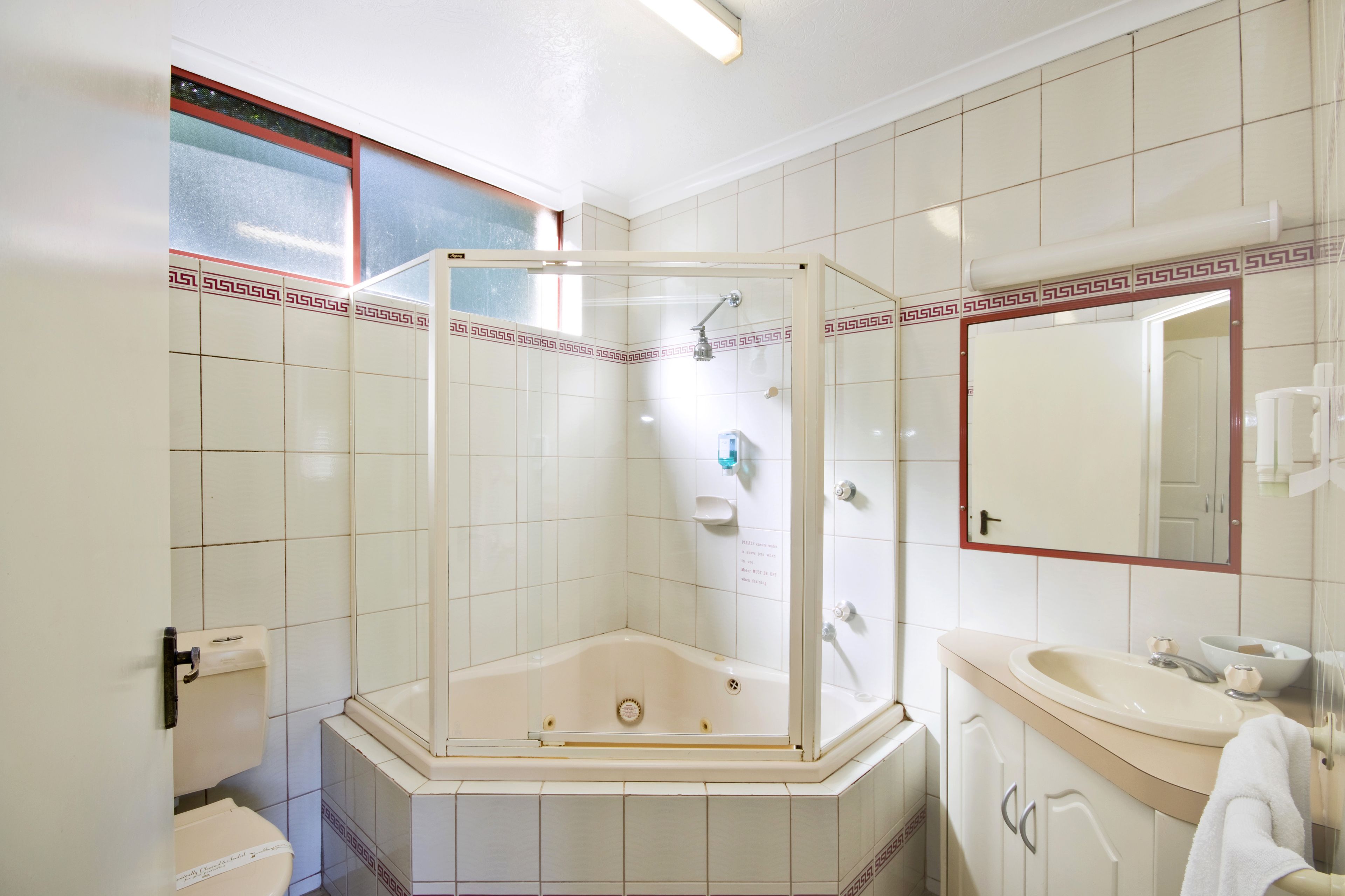 A bathroom with a glass-enclosed shower, a sink, and a toilet.