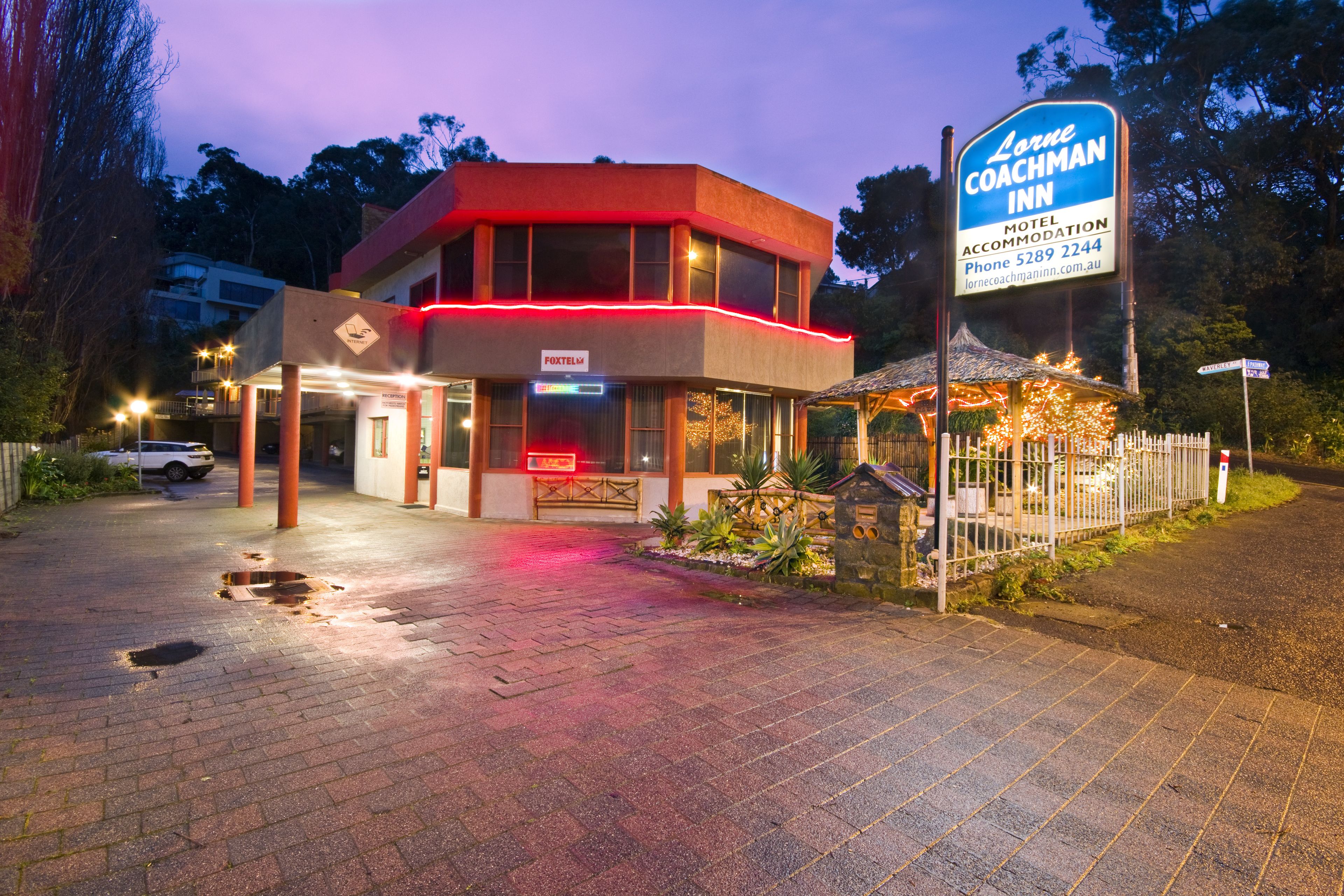 Ein Motel mit auffälliger Beschilderung, einer überdachten Außenbereich-Sitzgelegenheit und einem gepflasterten Eingang.