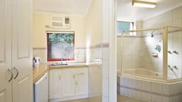 A bathroom with a shower, a sink, and a window.
