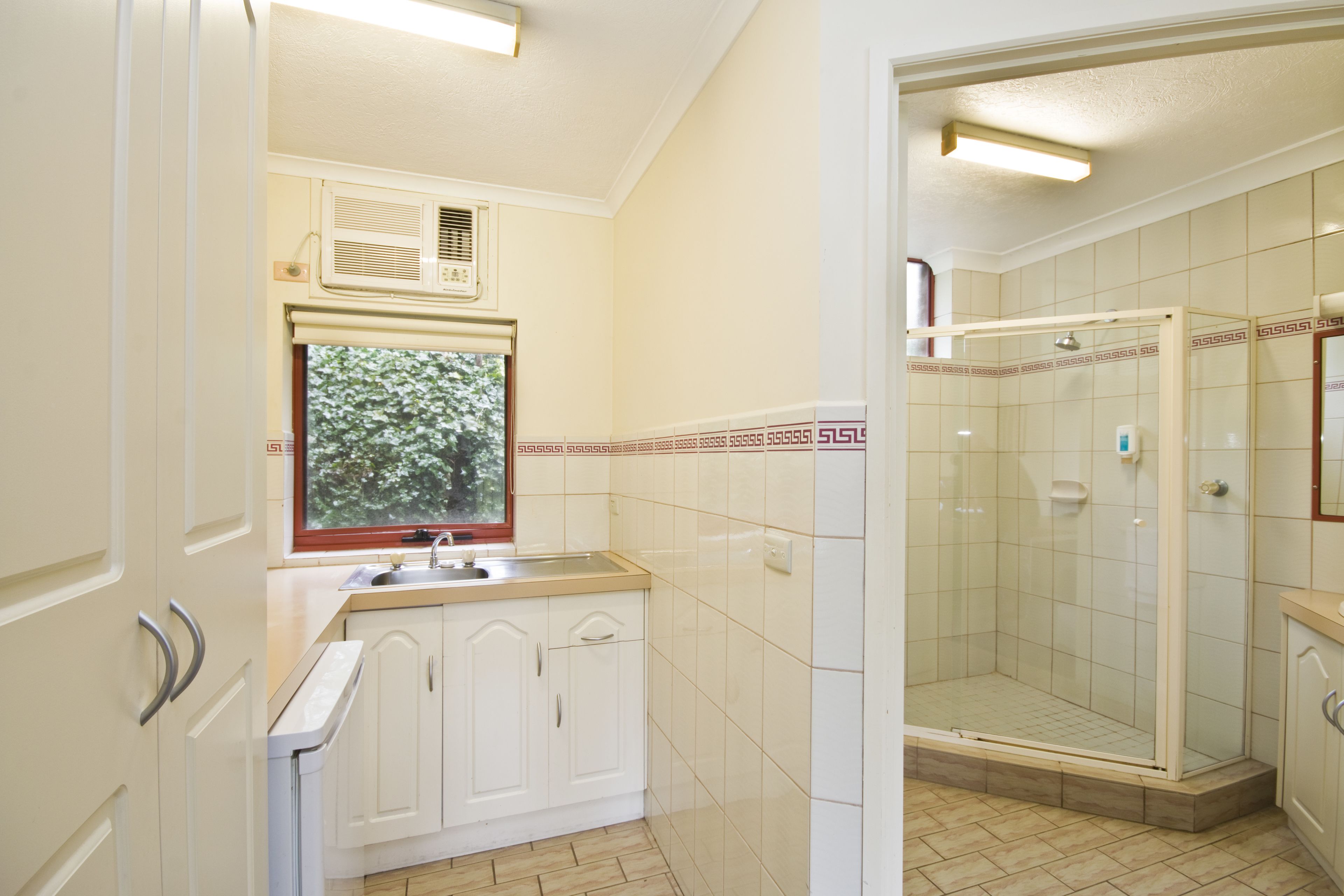 Un baño con ducha, ventana y lavamanos.