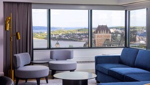 A modern hotel room with a large window offering a view of a historic building and a river.