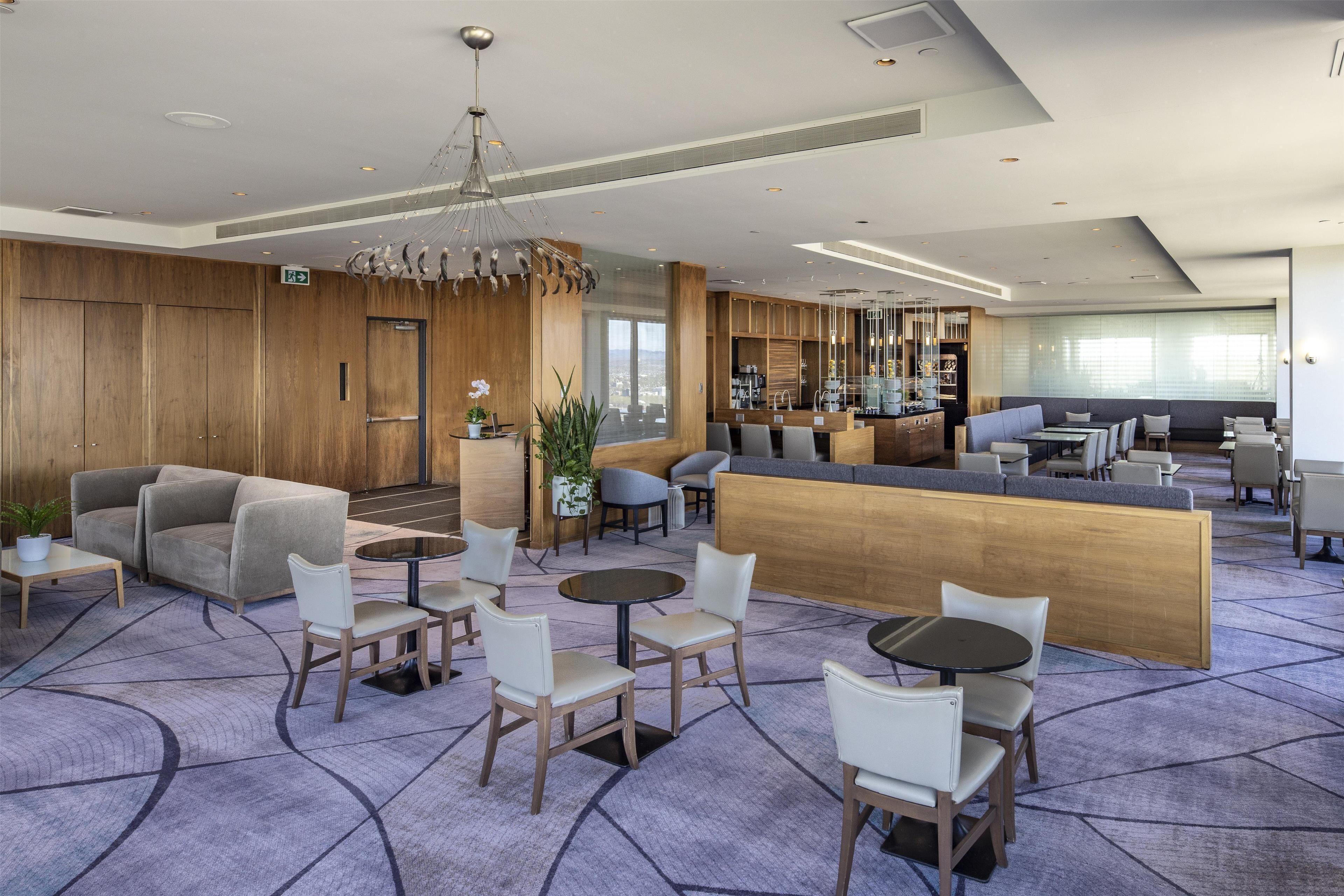 Een moderne hotellobby met een receptiebalie, zithoeken en een bar.