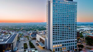 A tall, modern hotel building with a grid of windows and a "Hilton" sign on the top.