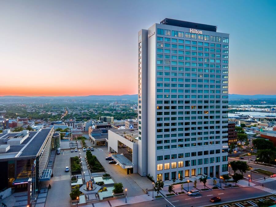 Un edificio moderno y alto de hotel, con una fachada de ventanas en forma de cuadrícula y un letrero con la palabra "Hilton" en la parte superior.