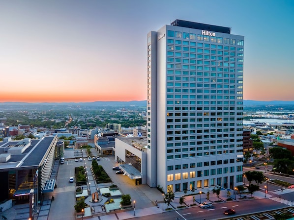 A tall, modern hotel building with a grid of windows and a "Hilton" sign on the top.