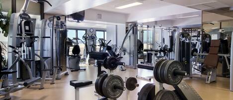 A gym with various exercise equipment, including treadmills, weight machines, and free weights.