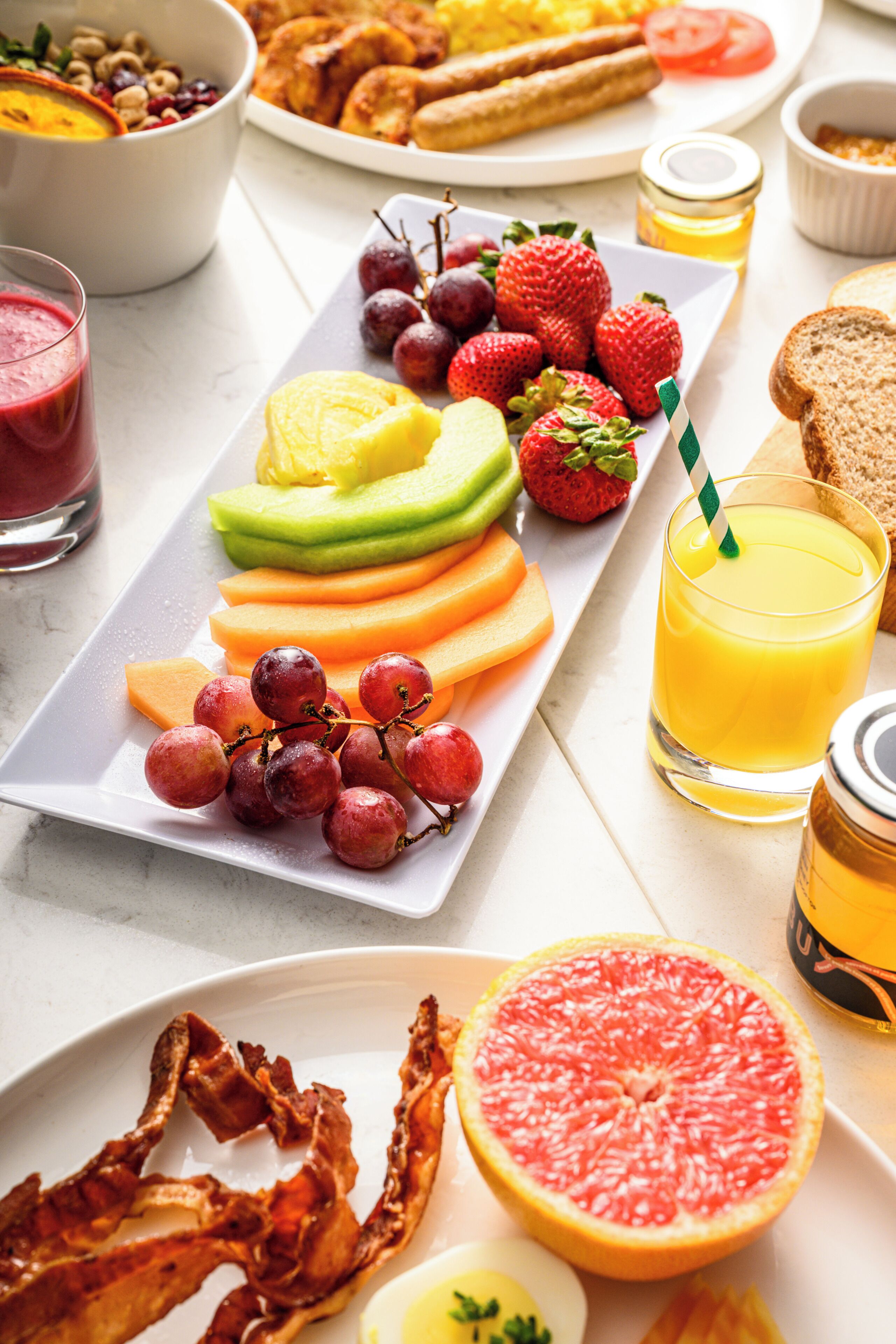 Una bandeja de desayuno con frutas, tostadas y tocino.
