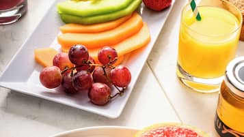 Una bandeja de desayuno con frutas, tostadas y tocino.