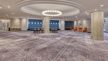 A spacious hall with a checkered floor, a central circular light fixture, and seating areas with chairs.