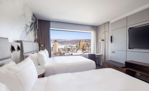 A hotel room with two beds, a large window with a city view, a flat-screen TV, and a small table. - Hilton Quebec (Québec City)