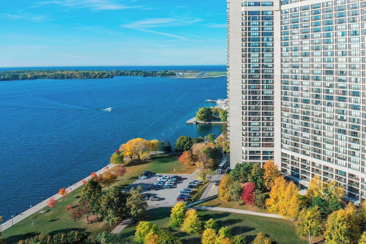 A high-rise hotel with a parking lot and autumn foliage.