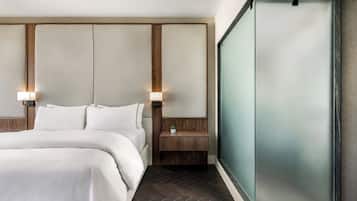 Een moderne hotelkamer met een groot bed, een houten hoofdbord en een wand van glas.