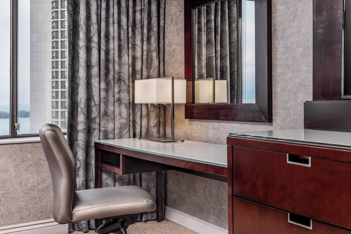 Habitación de hotel con escritorio, silla y un espejo grande.