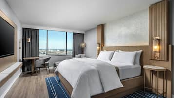 Una habitación de hotel moderna con una cama grande, un escritorio, una silla y un televisor.