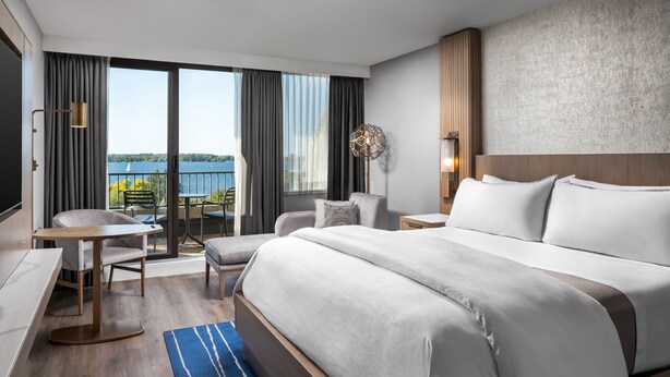 A hotel room with a large bed, a desk, a chair, a small table, and a view of the outdoors. - The Westin Harbour Castle, Toronto (Toronto)