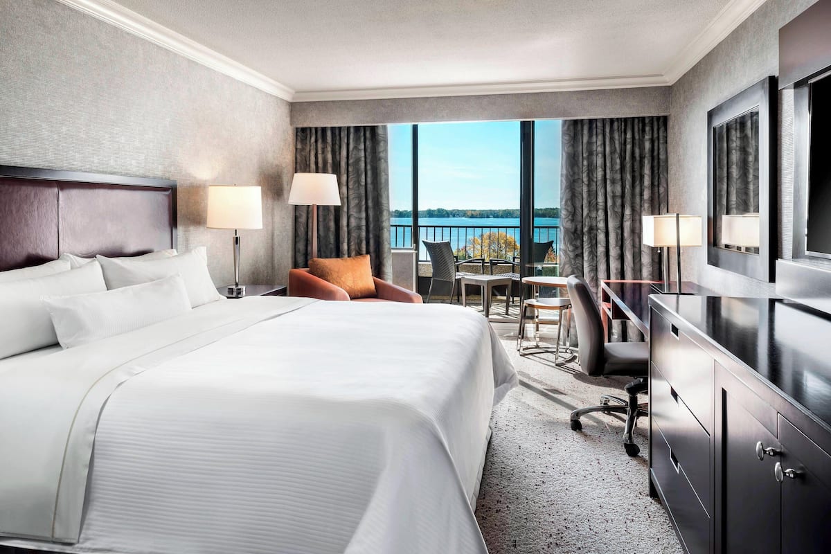 A hotel room with a large bed, a desk, a chair, and a view of the water.