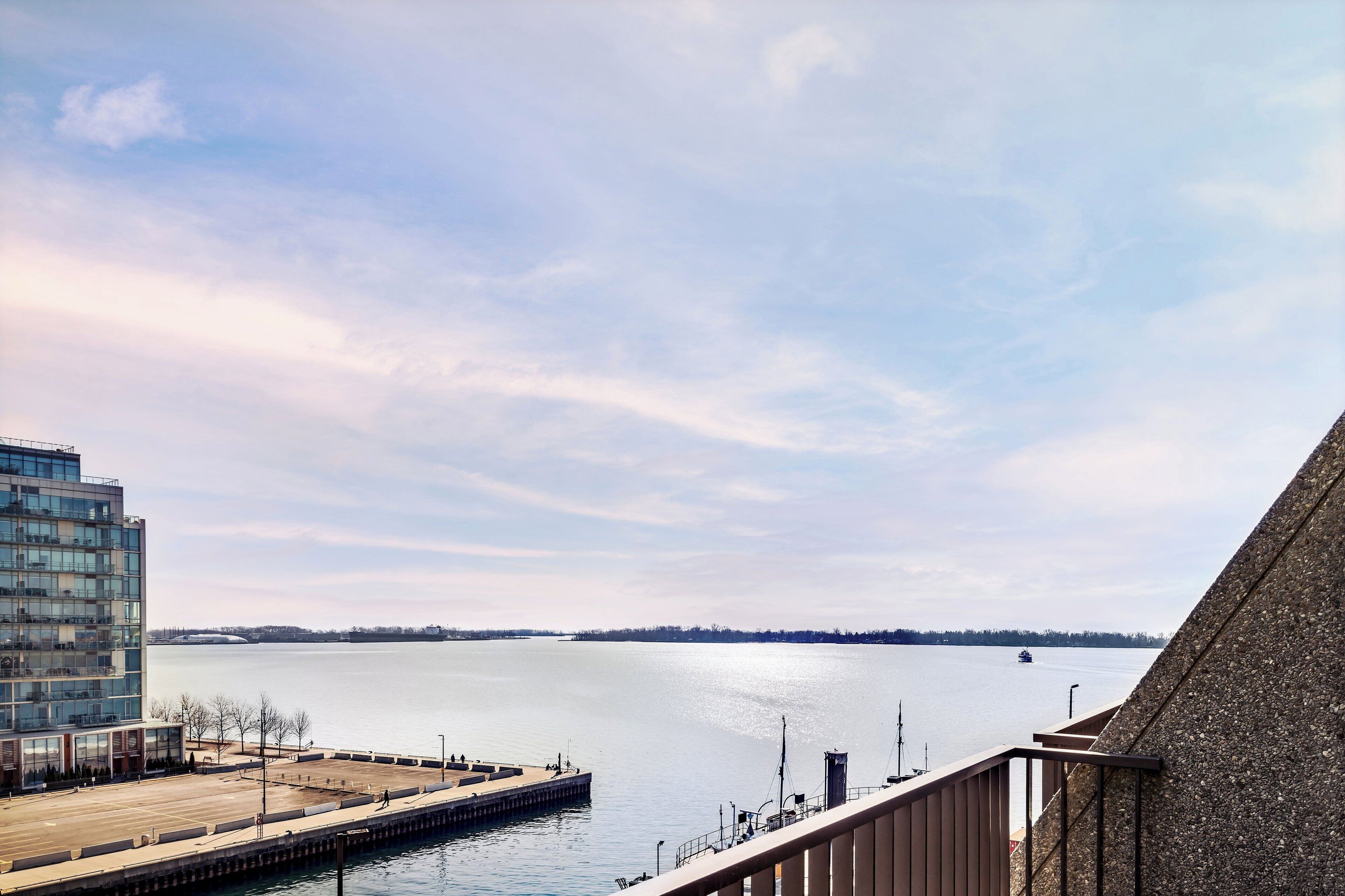 Blick auf das Wasser mit einem modernen Gebäude, einem Steg und einem klaren Himmel.