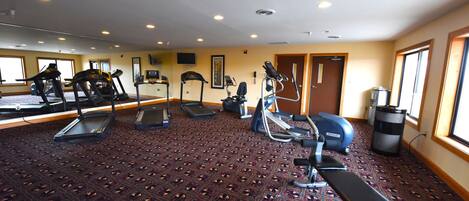 A gym with treadmills, elliptical machines, and a bench.