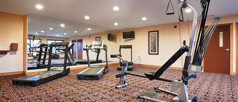 Een hotelgym met loopbanden, een roeimachine en een gewichtbank.