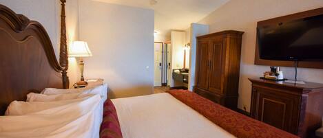 Una habitación de hotel con una cama grande, cabecera de madera, televisión y armario.