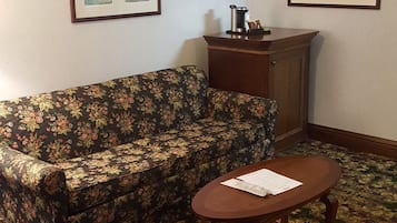 Una habitación con un sofá estampado con motivos florales, una mesa de centro de madera y dos cuadros en las paredes.