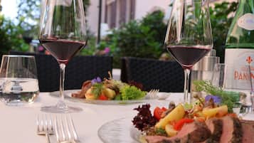 Una mesa de comedor con platos de comida, copas de vino y una botella de PANNIN.