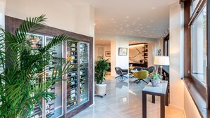 Un intérieur moderne avec un meuble à vin, un coin repas avec des chaises et une grande fenêtre.