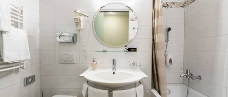 Un baño con inodoro, lavabo, espejo, toallero y ducha.