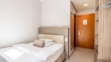 Un dormitorio con cama, cabecera de madera, una puerta y un escritorio pequeño.