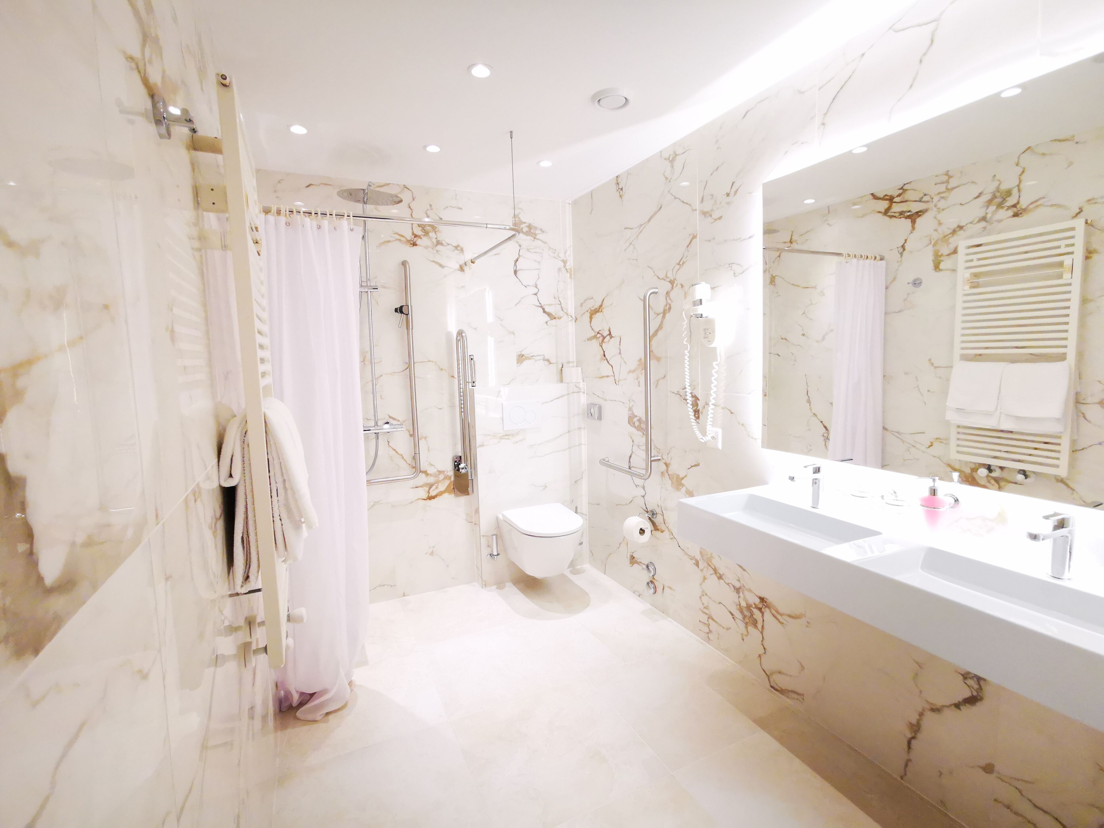 Une salle de bain moderne équipée d’une douche, de toilettes et d’un grand meuble-lavabo avec un miroir.