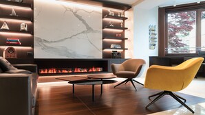 Un salon moderne doté d’une cheminée, d’un plancher en bois et d’un mur en marbre.