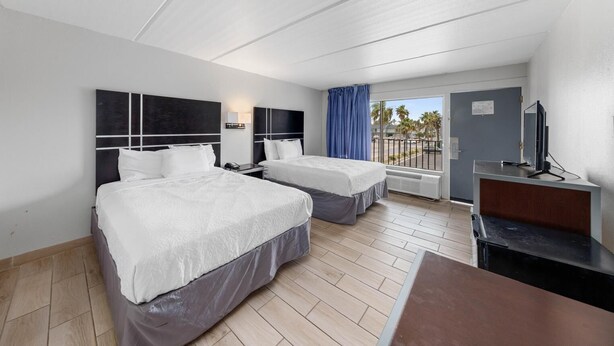 Une chambre d’hôtel avec deux lits, un bureau, une télévision et un balcon avec vue.
