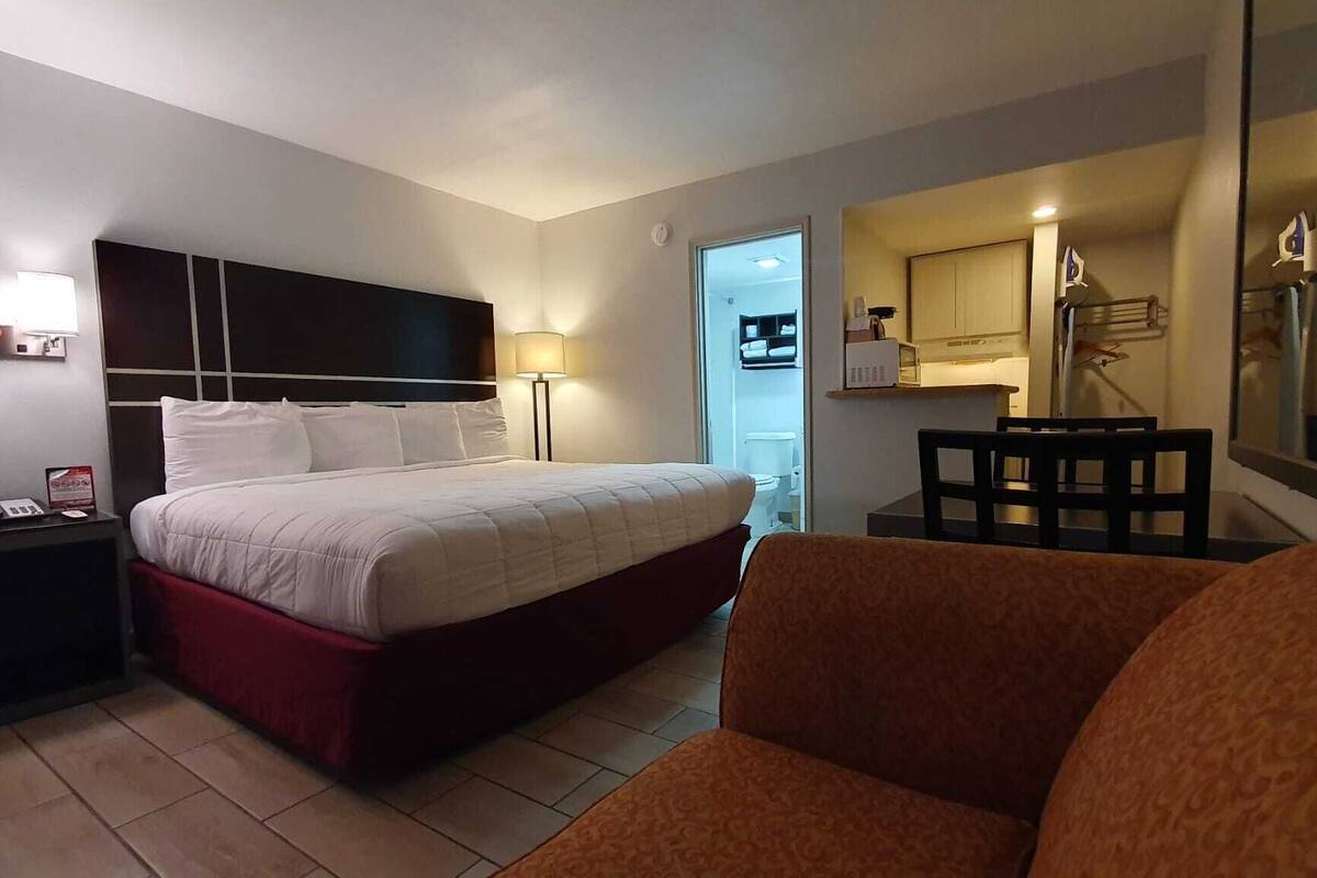Habitació d'hotel amb un llit, escriptori, cadira i una cuineta petita.