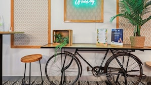 A room with a bicycle, a neon sign, a plant, and a menu on a table. - ibis Styles Paris République (Paris)