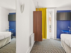 A hotel room with two beds, a TV, a bathroom, and a patterned floor. - ibis Styles Paris République (Paris)
