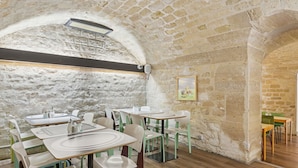 A rustic interior with stone walls, wooden floors, and simple white tables and chairs. - ibis Styles Paris République (Paris)