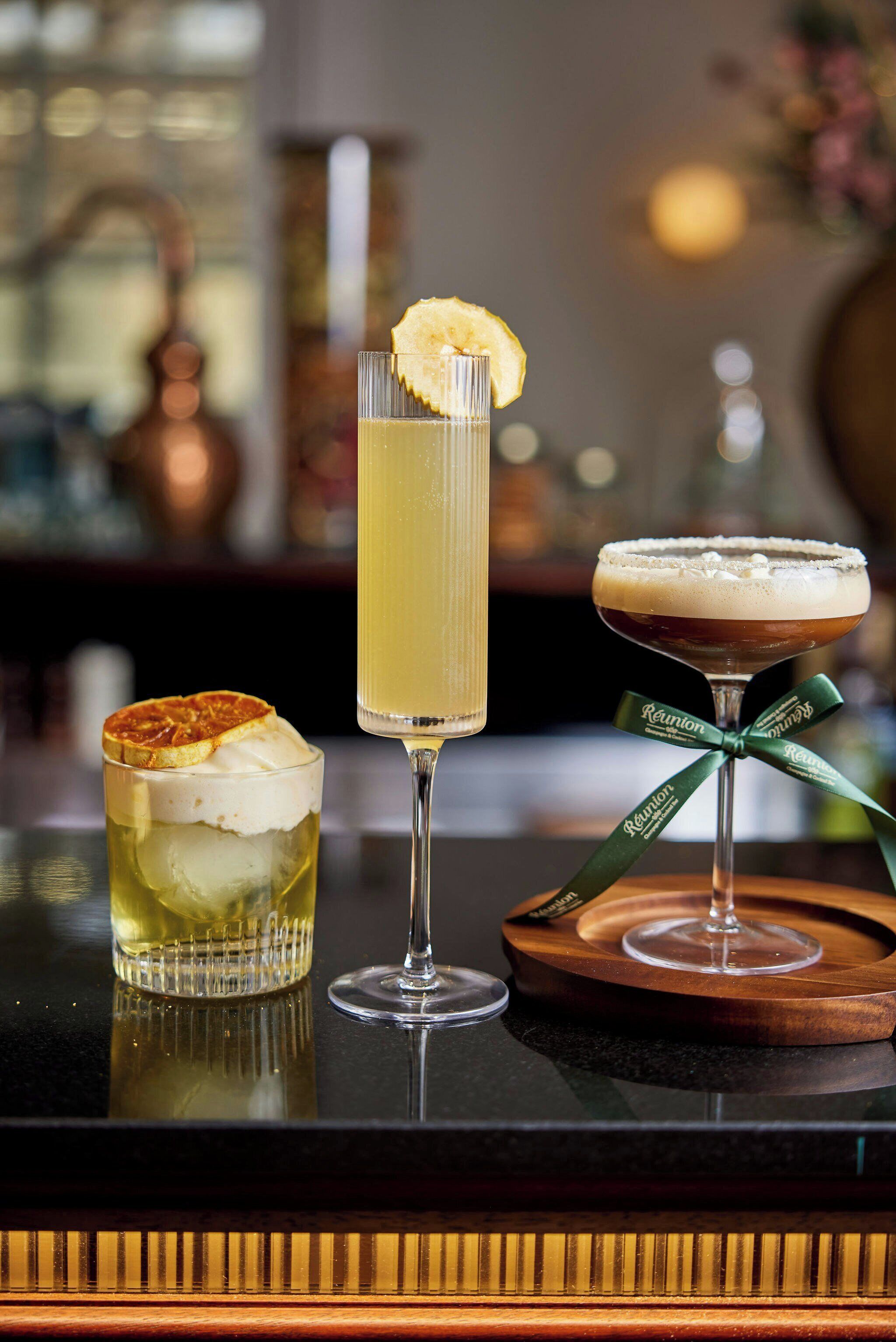 Drei Cocktails auf einer Bar, unscharfer Hintergrund.