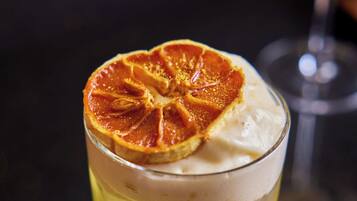 Un vaso con bebidas en capas y una rodaja de naranja deshidratada encima.