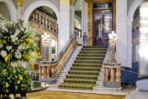 A grand staircase with marble steps and ornate railings leading to a reception area with a sign. - The Clermont London, Victoria (London)