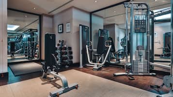 Ein modernes Fitnessstudio mit verschiedenen Trainingsgeräten, darunter ein Squat-Rack, Beinpresse und Kurzhanteln.
