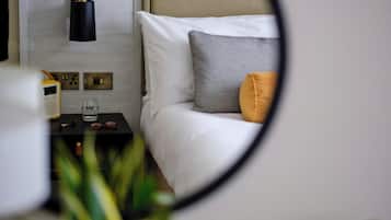 Ein Schlafzimmer mit einem Bett, einem Nachttisch mit Radio, einem Glas und einer Wandlampe.